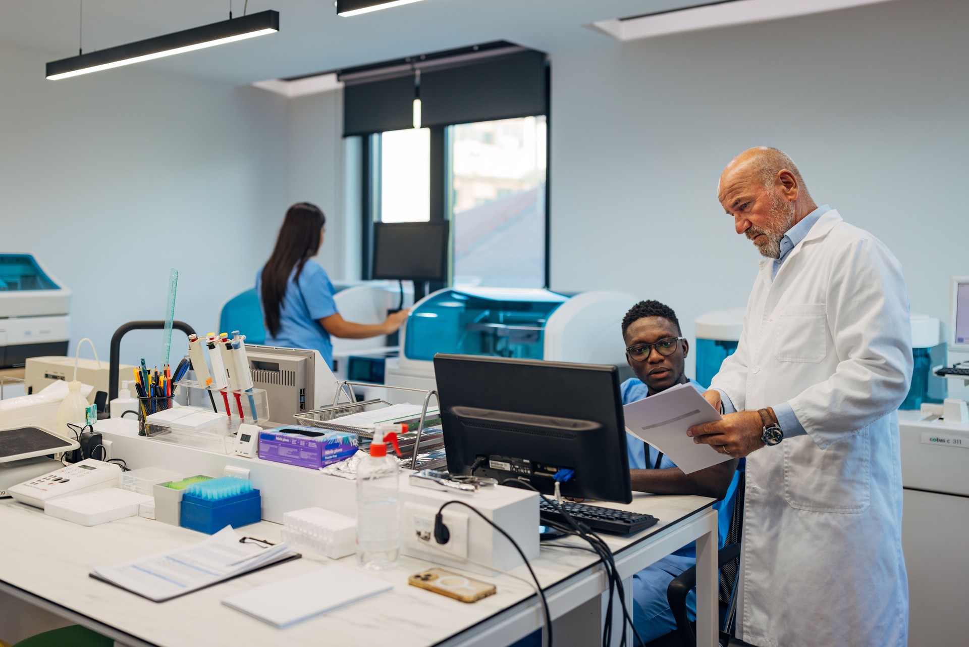 A black male technician is discussing with a senior biochemist about the blood results obtained in their laboratory